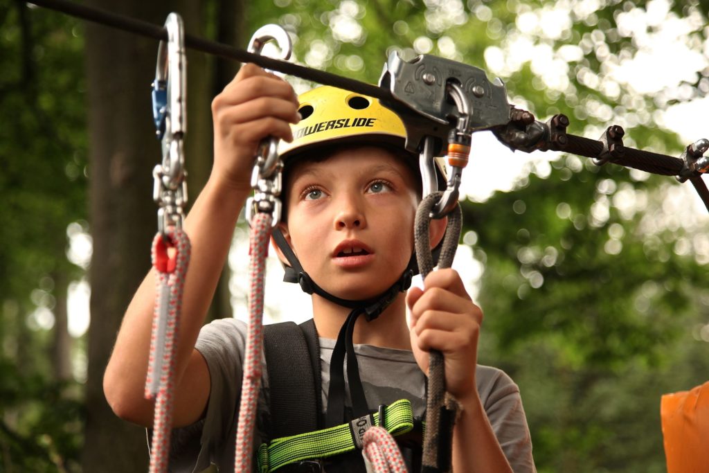 Child completing high ropes wearing a safety harness and helmet