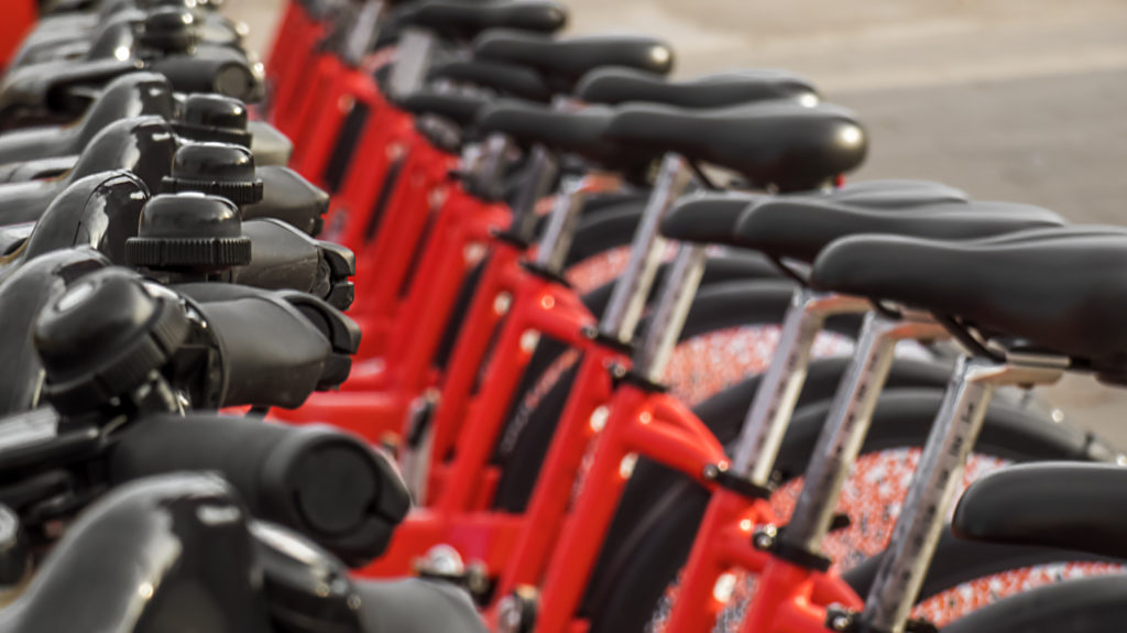 A row of red electric bikes charging outside
