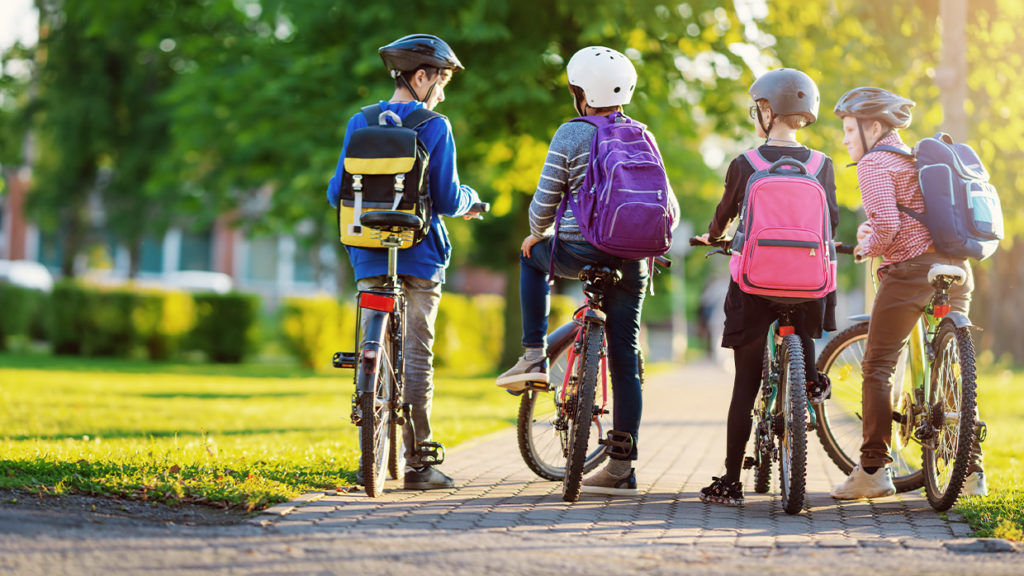 Children cycling safely to school together , wearing helmets and carrying backpacks, demonstrating healthy active and sustainable travel.